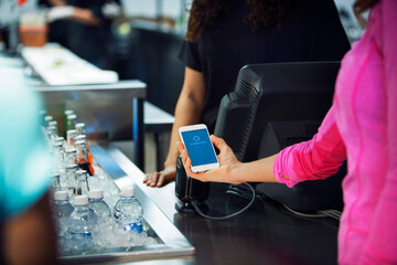 Cropped image of woman scanning smart phone while paying bill in restaurant