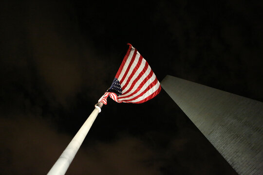 Low angle view of American flag by Washington Monument against sky