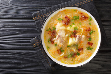 Delicious Polish sauerkraut soup with vegetables and ribs and bacon close-up in a plate on the table. horizontal top view from above