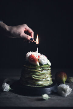 Cropped image of woman lightning candle on pancake