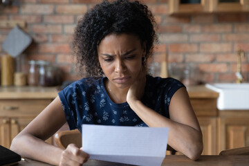 Close up unhappy African American young woman reading letter, document, frustrated businesswoman or...
