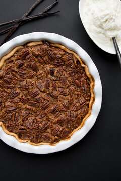 Overhead view of pecan pie by cream on table