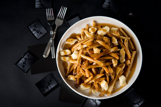 Overhead view of poutine in bowl with forks on table