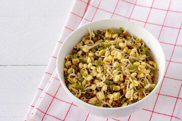 Sprouted mung beans in a bowl on white table. Healthy concept, macrobiotic food.