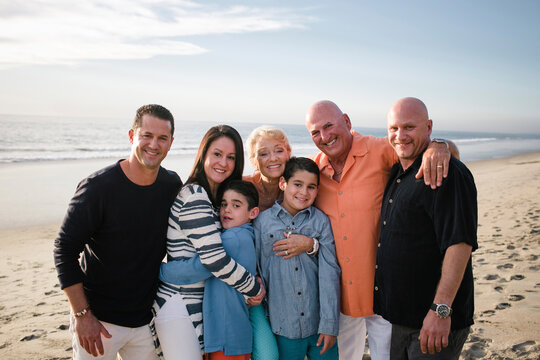 Portrait of happy family standing at beach against sky