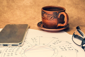 The workplace of an astrologer, magician and sorcerer of our time. Hobby during the coronavirus pandemic. Astrological charts and tables built with the help of modern gadgets, laid out on the table.