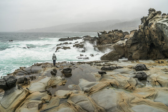 High angle view of man standing on rocks at beach against sky during foggy weather