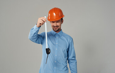 male builder with a measuring tape in his hands on a gray background