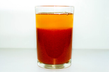 A glass of red tomato juice on a white background.
