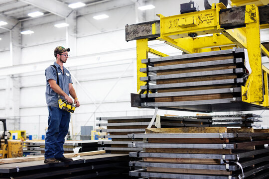 Worker operating overhead crane in metal Steel Mill