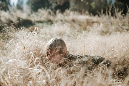 Boy hiding amidst plants on field at Yosemite National Park
