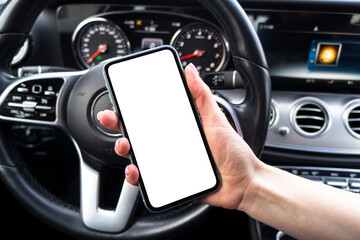 Female hand using smartphone in car. Smartphone in a car use for Navigate or GPS. Mobile phone with isolated white screen. Blank empty screen. Copy space. Empty space for text.