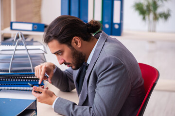 Young male employee unhappy with excessive work in the office