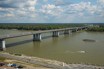 Bridge over a wide river. The Ob River in Russia. A motor ship is sailing along the river.