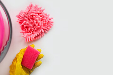 Pink sponge and microfiber cloth for cleaning the house of the apartment. Yellow gloves for washing and a bucket. Copy space, place for text on a white background.