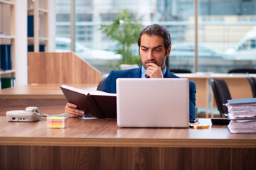Fototapeta premium Young male employee reading book in the office