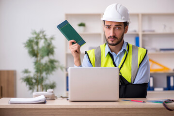 Young arm injured male architect working in the office