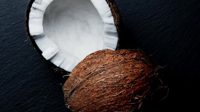 Split into two halves coconut on a black background .Fresh coconut rotating on a black background.
