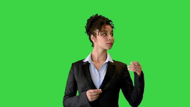 African American lady in a suit pointing at blank spaces on a Green Screen, Chroma Key.