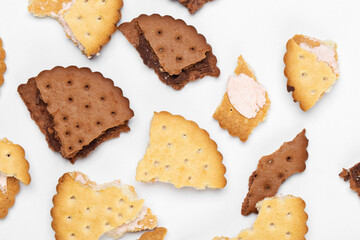 Pieces of chocolate chip cookies and biscuits with filling on a white plate close-up. Top view.