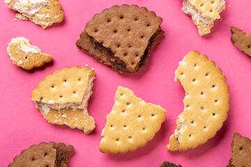 Pieces of chocolate chip cookies and biscuits with filling on a pink background close-up. Top view.