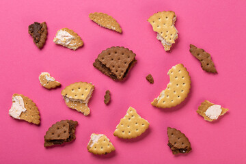 Pieces of chocolate chip cookies and biscuits with filling on a pink background close-up. Top view.