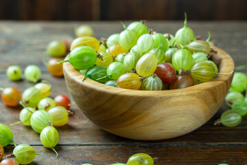 Ripe gooseberry in a wood plate, place for text, top view