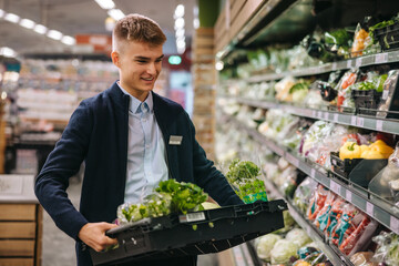 Shop assistant restocking the produce section shelves