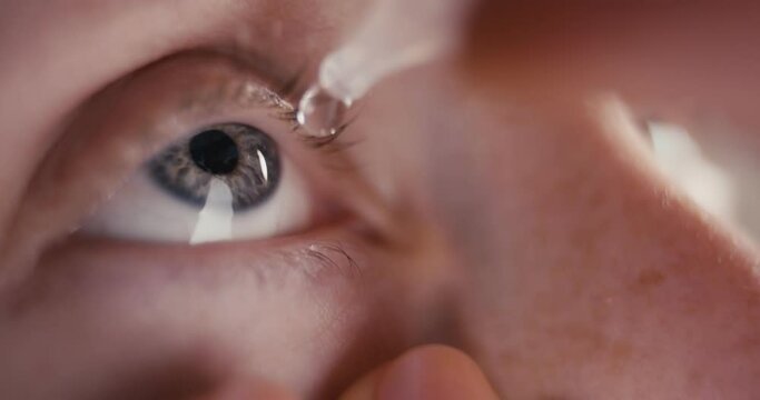 Woman use medical eye drops care in hand blue macro fingers close up