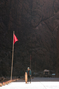 Portrait of woman with skateboard standing on road against mountain
