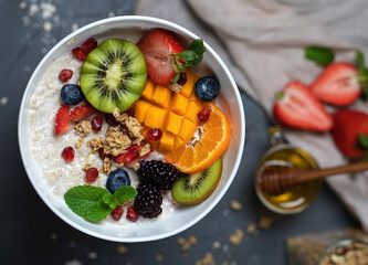 Oatmeal in a bowl with colourful fruit topping top view. Bright healthy breakfast concept. High quality photo