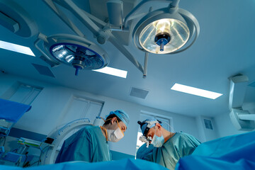 Surgeons operating patient. Back view of surgeons team looks at monitors while performing operation in hospital