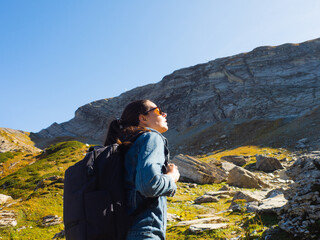 young female tourist with a backpack is walking in the mountains, traveling in national parks.