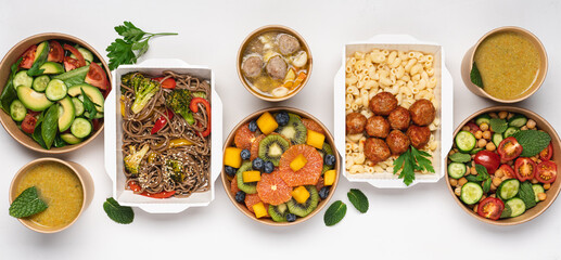 Cooked food in paper eco-friendly containers on white background. Food delivery for home or office. Vegetable, fruit salads, soups, meat and side dishes