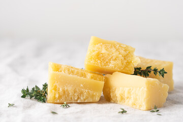 Pieces of parmesan cheese with thyme. Traditional Italy hard cheese. Light background with copy space, table with gray linen tablecloth