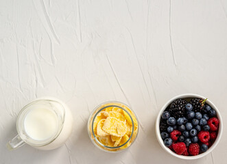 Milk, cornflakes, fresh berries - ingredients for a snack or breakfast on a white background
