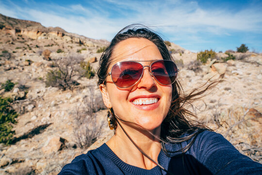 Portrait of cheerful woman wearing sunglasses at desert