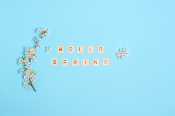 Blooming cherry branches with white flowers, text hello spring on a blue background