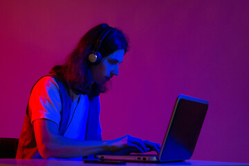 Funny guy gamer playing on a laptop. A young man with headphones