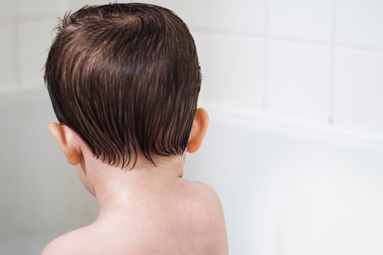 Rear view of shirtless boy in bathtub at home