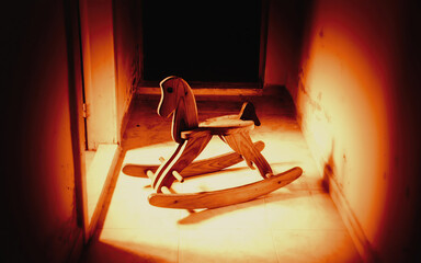 A creepy rocking horse, abandoned in a basement room. Nobody in sight. Blood red lighting.

