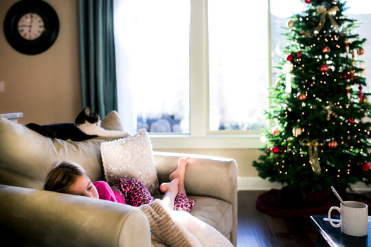 Girl sleeping on sofa by Christmas tree at home