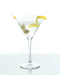 Martini mixed drink with lemon peel garnish and olives on a white background.
