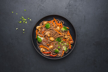 Vegan Stir fry with vegetables and mushrooms  in black bowl. Close up view. Black slate background