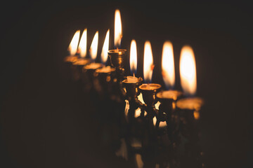 Close-up of Hanukkah Menorah candles glowing in darkroom