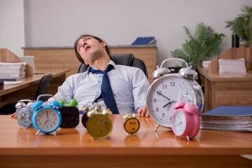 Young male employee sleeping in the office in time management co