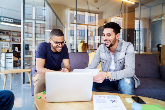 Smiling male coworkers discussing in meeting at office