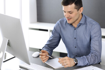 Businessman working with computer in modern office. Headshot of male entrepreneur or company...