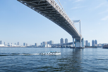 Fototapeta premium 青空を背景にレインボーブリッジの下を白い波を立てて進む船