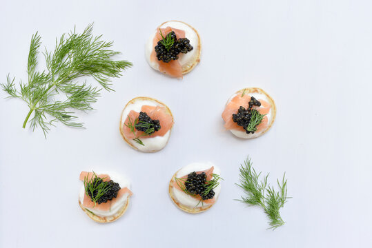 High angle view of blinis with salmons and caviars on white table